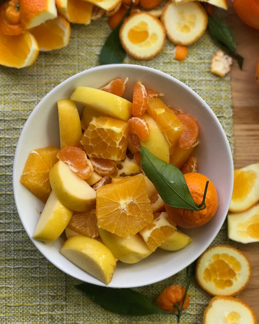 Cut oranges and apples in a white bowl